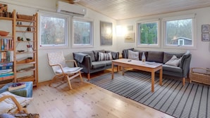 A cozy living room with a wooden ceiling, a sofa set, a coffee table, and a bookshelf.