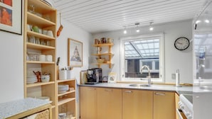 A modern kitchen with wooden cabinets, a built-in coffee machine, and a large window providing natural light.
