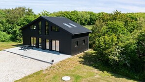 A modern black house with a sloped roof, large windows, and a gravel driveway. - "Markhild" - 300m to the fjord by Interhome (Hurup Thy)