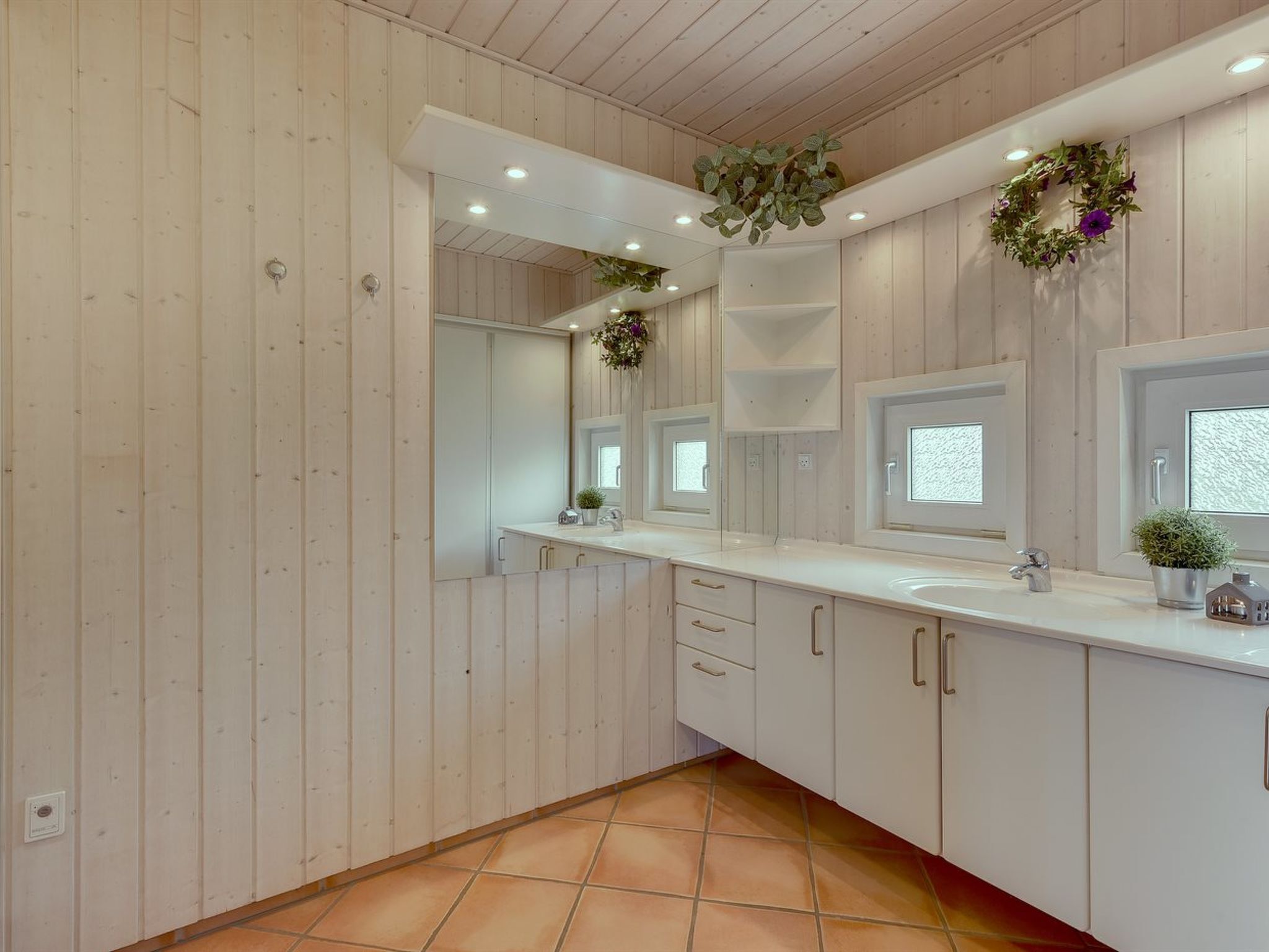 A modern bathroom with wooden panel walls, a white countertop, and a large mirror.