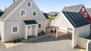 Een modern gebouw met een schuin dak, een klein terras en een grindpad.