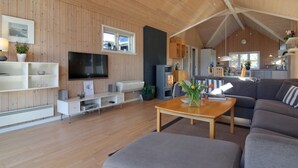 Un salon moderne avec un plafond en bois, un téléviseur à écran plat, un canapé et une table basse.