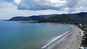 A coastal beach with a clear view of the ocean, a sandy shoreline, and a backdrop of green hills. - Akkaw Baler Hometel (Baler)