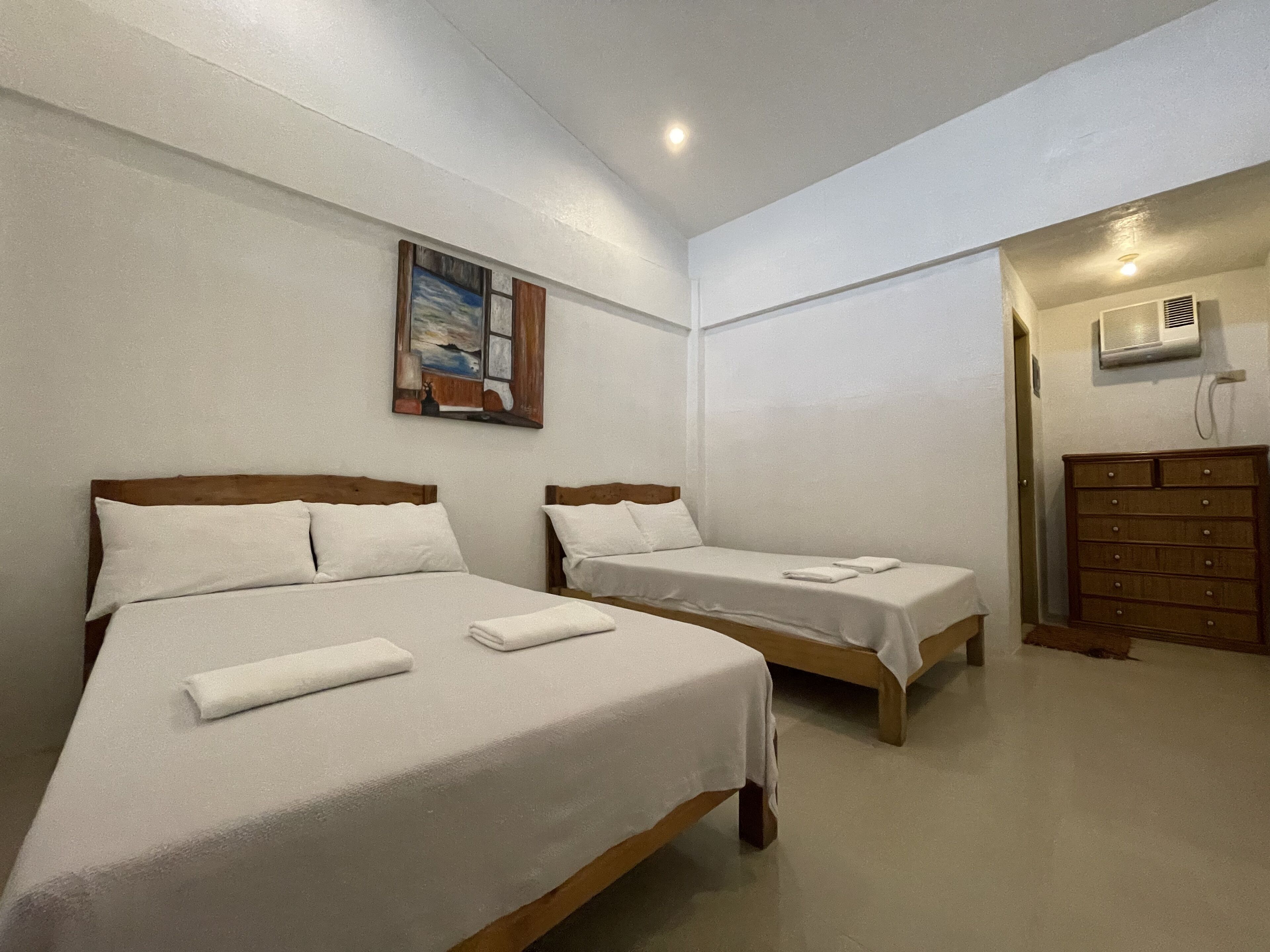 Habitación de hotel con dos camas, un cuadro en la pared y un aparador.