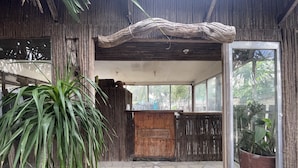 A reception area with a wooden reception desk, a large potted plant, and a tiled floor. - Akkaw Baler Hometel (Baler)