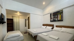A hotel room with two single beds and a sofa bed, a TV mounted on the wall, and a painting above the beds. - Akkaw Baler Hometel (Baler)