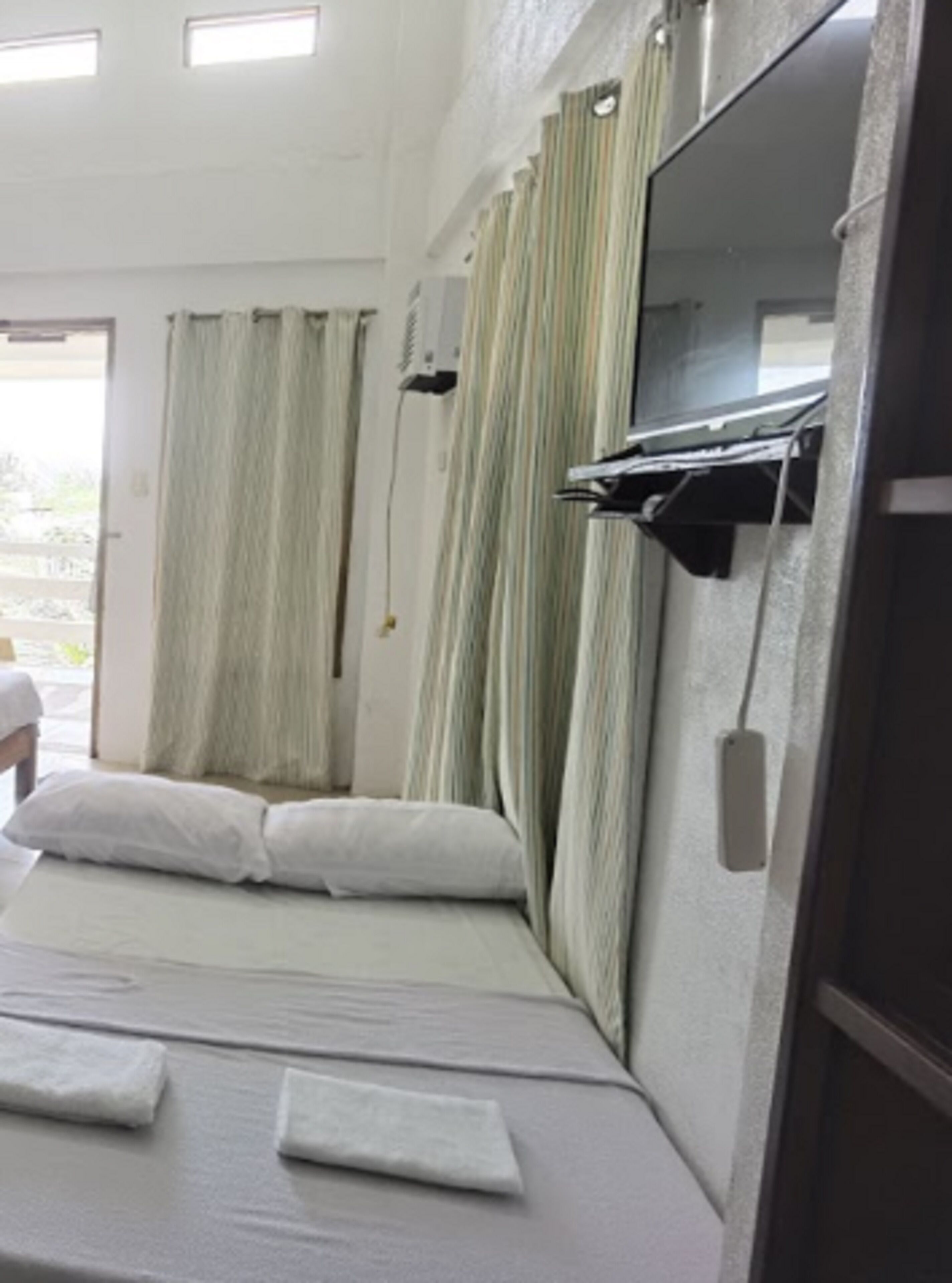 A hotel room with a bed, curtains, a mirror, and a window.