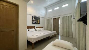 Habitación de hotel con dos camas, una puerta de madera, un cuadro en la pared y un televisor fijado a la pared.