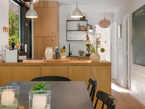 Een moderne keuken met houten kastjes, een centraal eiland, hanglampen en een prikbordwand.
