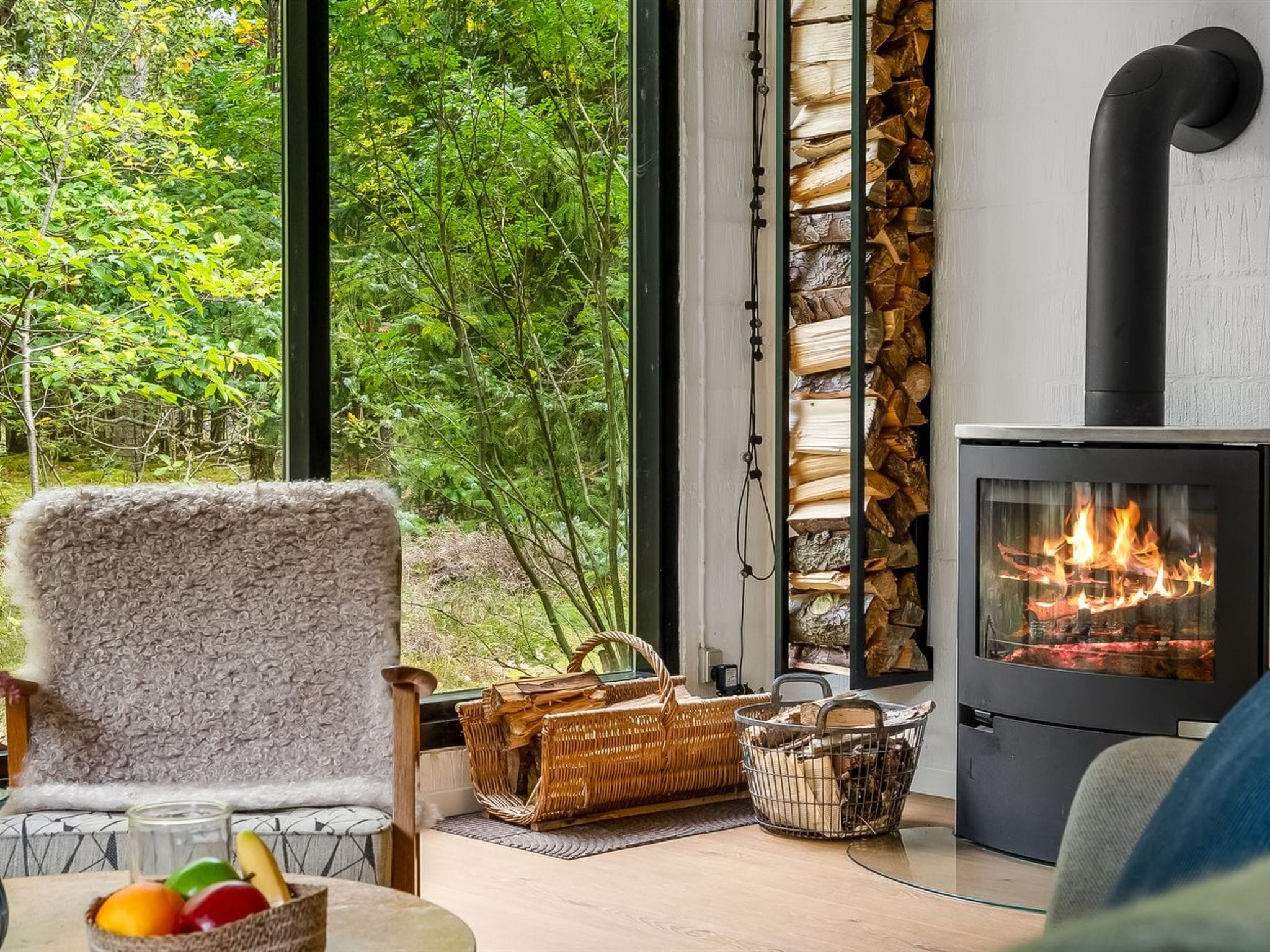 A cozy living room with a large window, a fireplace, and a view of the outdoors.
