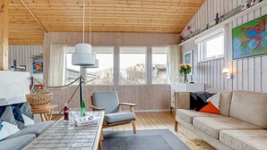 A cozy room with a wooden ceiling, a sofa, a dining table, and a window with a view of the outdoors. - "Kulle" - 200m from the sea by Interhome (Saltum)