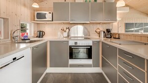 Una cocina moderna con vigas de madera en el techo, armarios grises, un horno Bosch y un microondas.