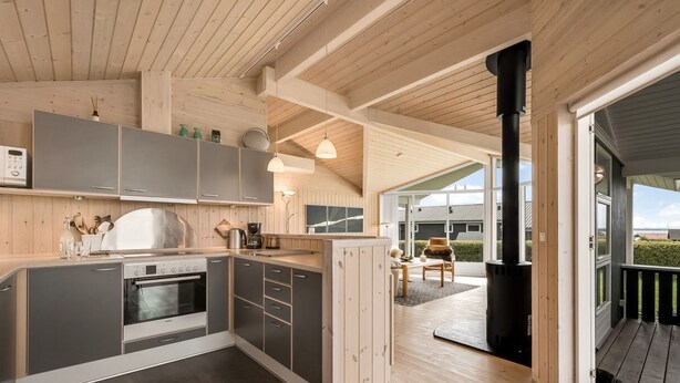 Una cocina moderna con armarios grises, horno empotrado y un amplio ventanal con vistas a una terraza.
