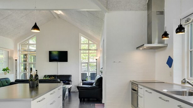 A modern kitchen with white cabinetry, a large island with drawers, a built-in oven, and a stainless steel sink.