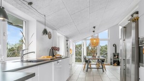 Una cocina moderna con una isla grande, electrodomésticos de acero inoxidable y vistas al exterior.