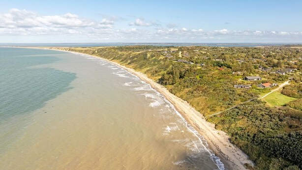 An aerial view of a coastal area with a sandy beach, residential buildings, and a clear sky. - "Engelbertine" - 210m to the fjord by Interhome (Struer)