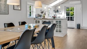 A modern kitchen with white cabinetry, a wooden dining table, and black chairs. - "Engelbertine" - 210m to the fjord by Interhome (Struer)