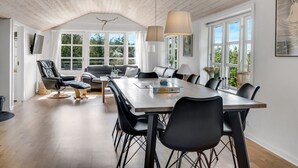 A spacious dining area with a long table and multiple chairs, a sofa, and a television mounted on the wall. - "Engelbertine" - 210m to the fjord by Interhome (Struer)