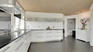 A modern kitchen with white cabinetry, a black countertop, and a wooden ceiling. - "Bibbi" - 20m to the fjord by Interhome (Ulfborg)