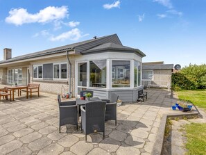 Une maison moderne dotée d’un patio comprenant une table et des chaises, un espace salon couvert et une antenne parabolique.