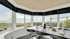 A modern dining area with a large table, black chairs, and a view of the sea. - "Bibbi" - 20m to the fjord by Interhome (Ulfborg)