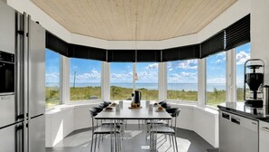 A modern kitchen with a large dining table, black chairs, and a coffee machine. - "Bibbi" - 20m to the fjord by Interhome (Ulfborg)