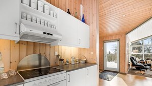A modern kitchen with white cabinetry, a stainless steel stove, and a built-in oven. There are shelves above the stove holding various kitchen items.