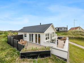 A modern house with a large glass door, a deck, and a surrounding grassy area.