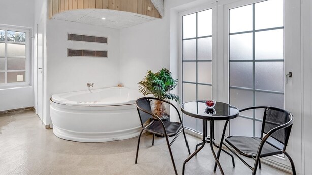 A modern bathroom with a freestanding bathtub, a small round table with two chairs, and a potted plant. - "Thana" - 1.4km from the sea by Interhome (Ulfborg)