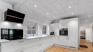 A modern kitchen with white cabinetry, a black range hood, and a built-in oven. - "Thana" - 1.4km from the sea by Interhome (Ulfborg)