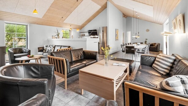 A spacious living area with a high ceiling, wooden beams, and a dining area with modern furniture. - "Benthe" -  from the sea by Interhome (Ulfborg)
