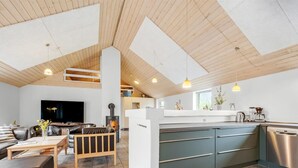 A modern living space with a fireplace, a dining area, and a kitchen with a dishwasher. - "Benthe" -  from the sea by Interhome (Ulfborg)
