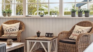 A cozy seating area with wicker chairs and a small table, featuring a window with potted plants and a view of greenery outside. - "Ekatarina" - 125m from the sea by Interhome (Juelsminde)