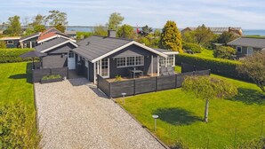 A modern residential area with houses featuring dark roofs and white trim, surrounded by well-maintained lawns and a clear view of the sea. - "Ekatarina" - 125m from the sea by Interhome (Juelsminde)