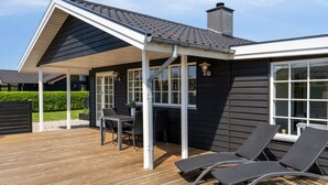 A modern house with a covered patio, a dining area, and lounge chairs. - "Ekatarina" - 125m from the sea by Interhome (Juelsminde)