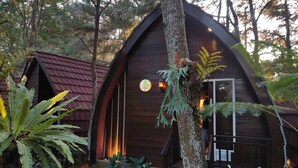 A wooden cottage with a red roof, surrounded by lush greenery and a sign indicating it is a 'Plaza Cottage 3'. - Pijar Resort Powered by Cocotel (Colo)