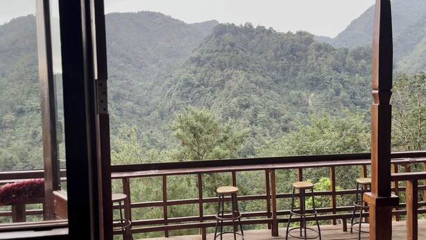 A balcony with wooden railings and two stools, overlooking a mountainous landscape with dense greenery. - Pijar Resort Powered by Cocotel (Colo)