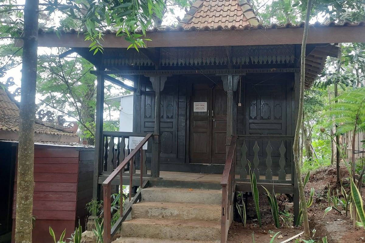 A traditional wooden structure with a tiled roof, a wooden staircase leading to a door, and a sign indicating it is a resting place for travelers.