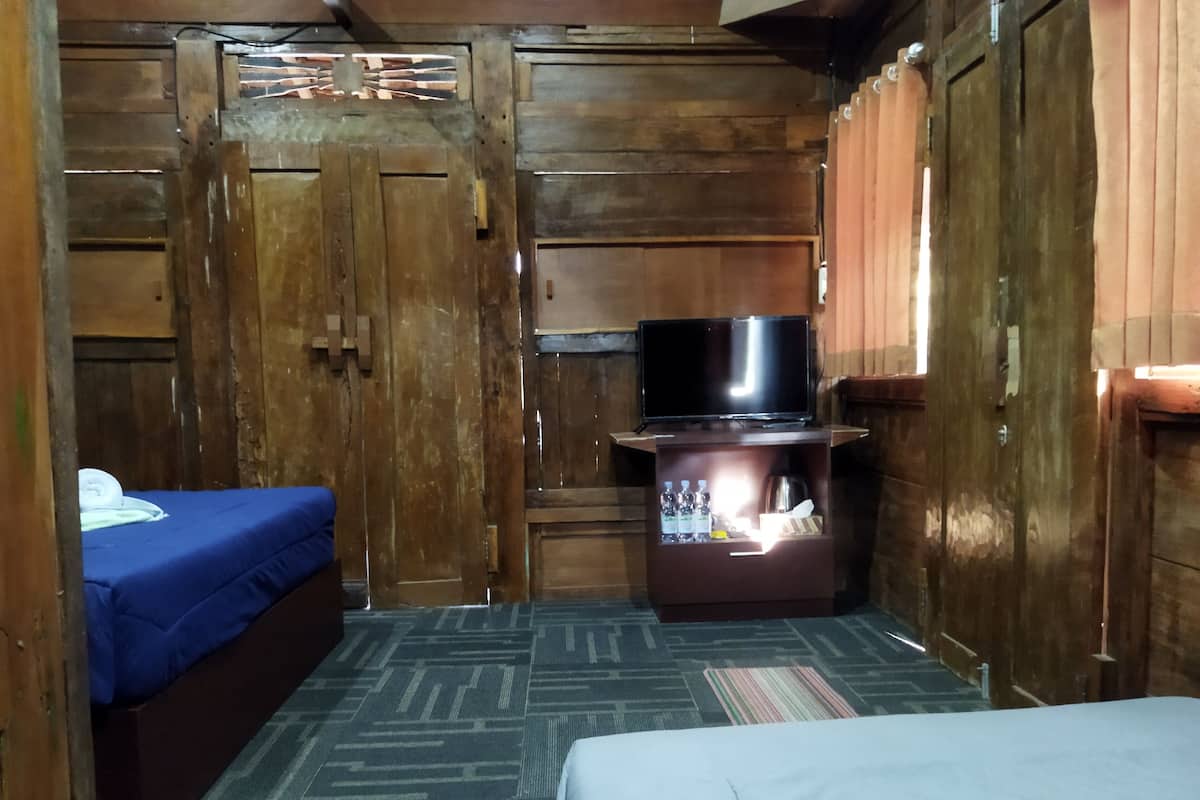 A compact room with a bed, a small seating area, a television, and a cabinet with bottles.