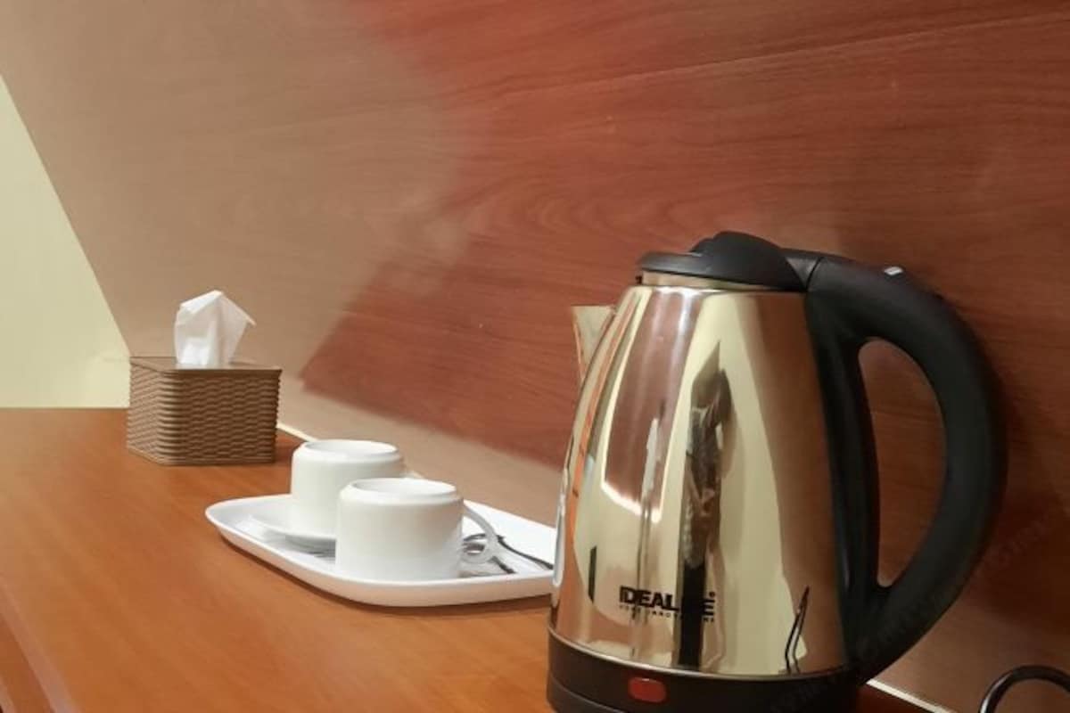 A stainless steel kettle with a black handle on a wooden table.