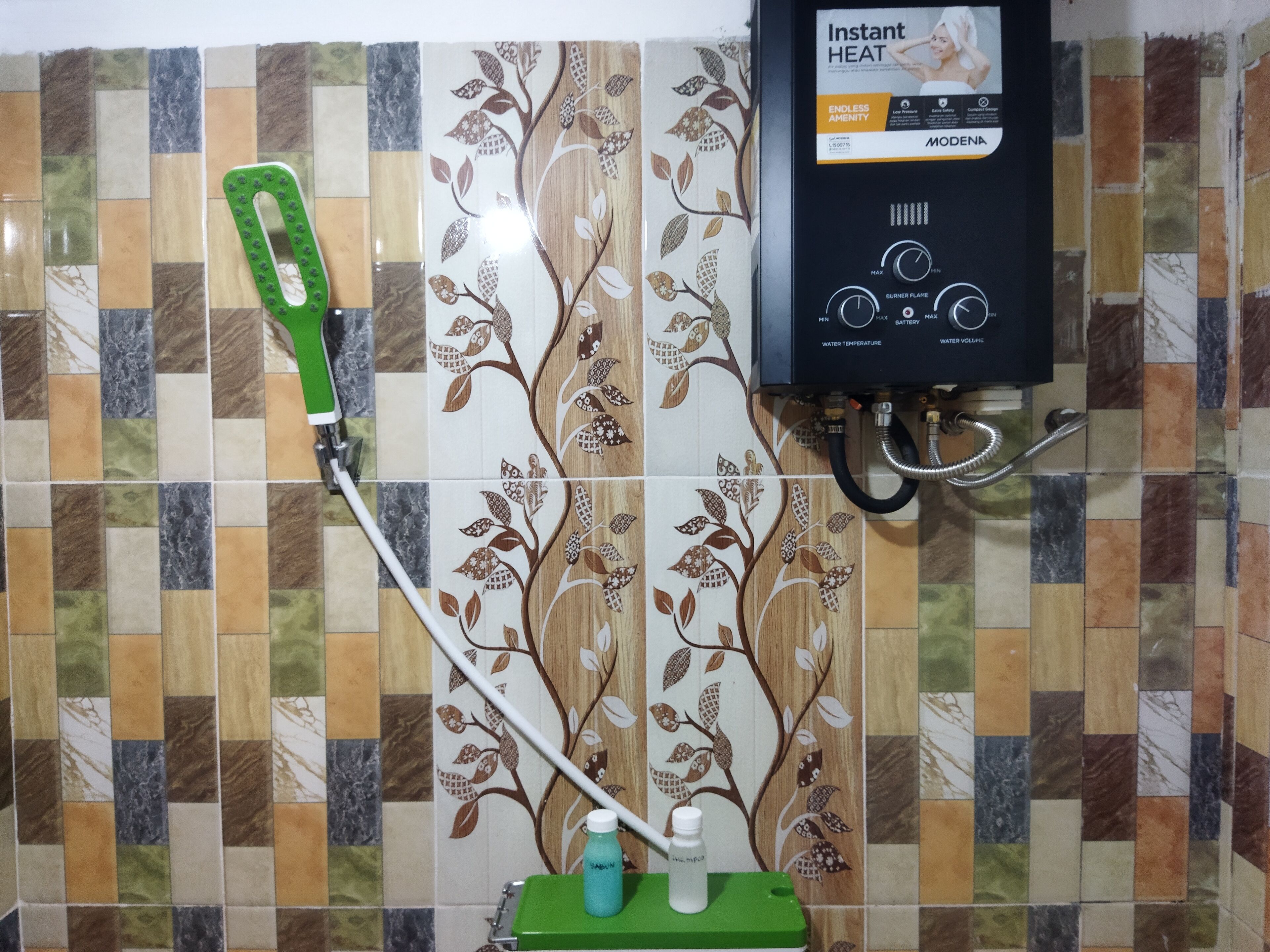 A bathroom with a shower, a green handheld showerhead, and a wall-mounted heater.