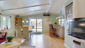 Amplia sala de estar con una mesa de comedor, sillas, sofá, televisor y una cocina con estufa y alacenas.