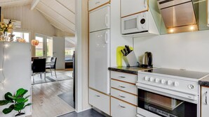 A modern kitchen with white cabinets, a microwave, a stove, and a sink.