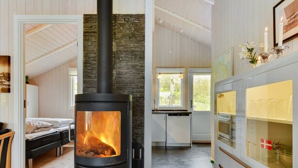 A modern living space with a wood-burning stove, a cozy seating area, and a kitchen with a view.