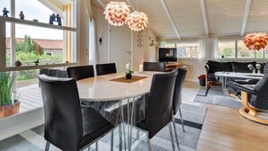 A modern dining area with a round table, black chairs, and pendant lights.