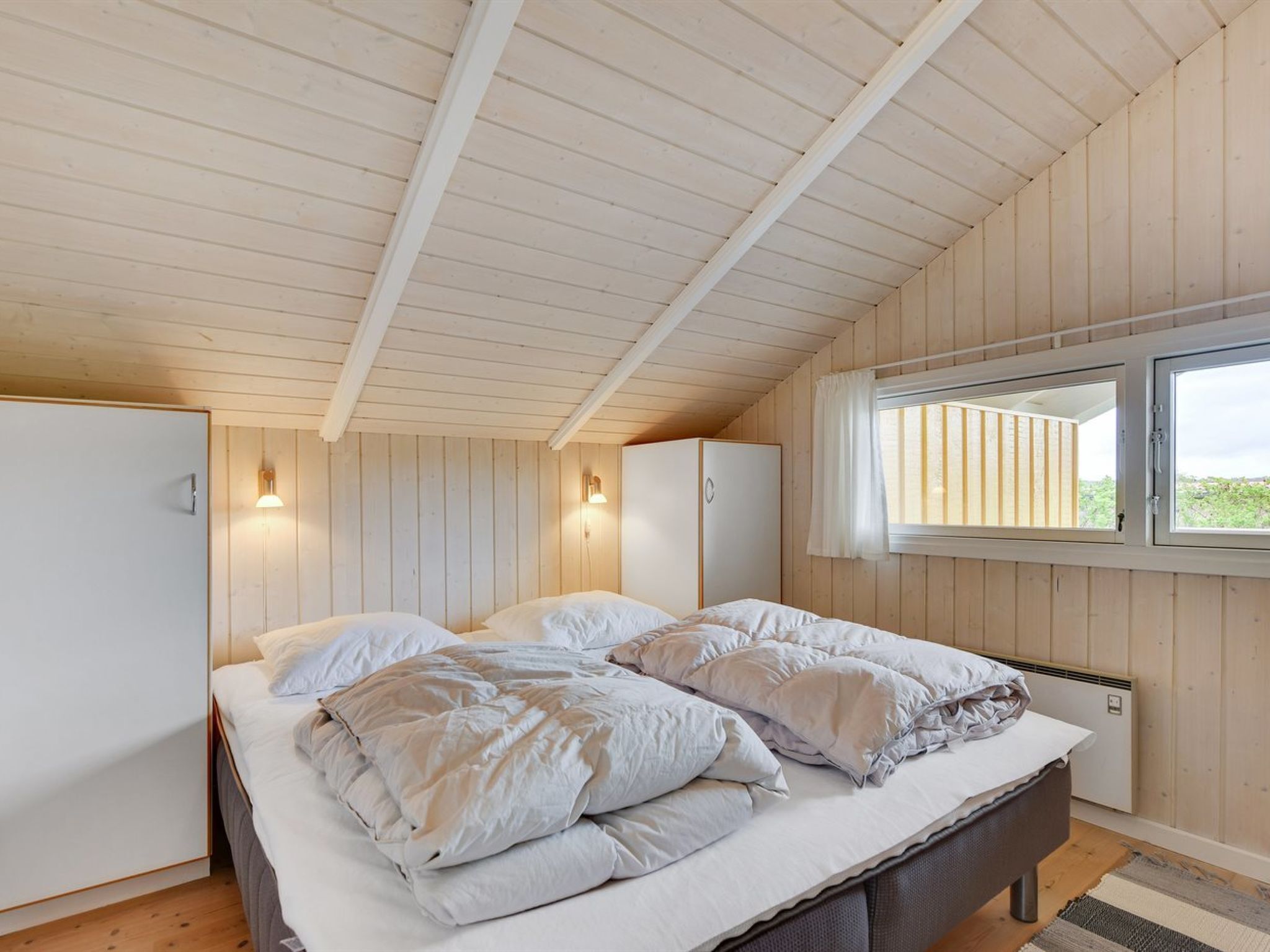 Une chambre à coucher avec un lit, deux tables de chevet et une fenêtre avec des rideaux.
