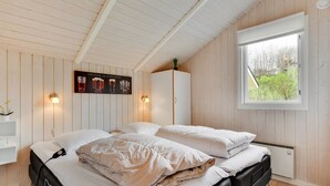 A bedroom with a bed, a wardrobe, a window, and a wall-mounted poster.