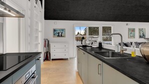 Eine moderne Küche mit schwarzem Arbeitsplatz, Edelstahlgeräten und einem Fenster mit Blick ins Freie.