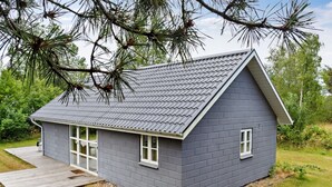 Ein kleines, eingeschossiges Haus mit grauen Ziegelwänden, einem geneigten Dach und einer Veranda.