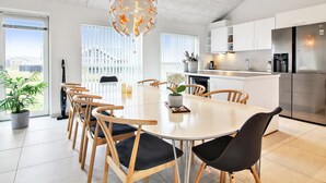 Een moderne keuken met witte kastjes, een roestvrijstalen koelkast en een eethoek met een ronde tafel en stoelen.